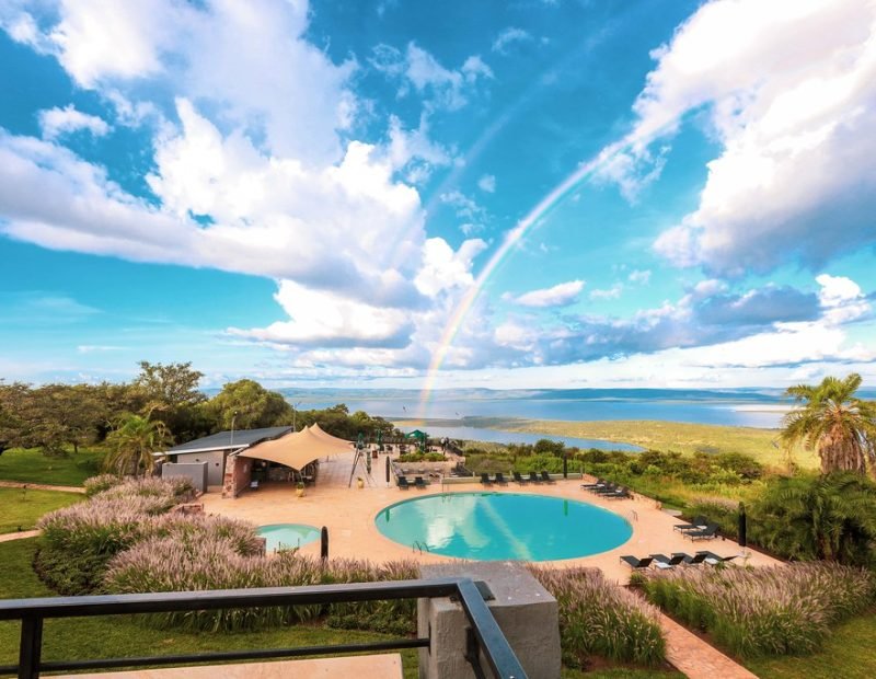 Lodge pool terrace with rainbow over lake in Akagera, Rwanda