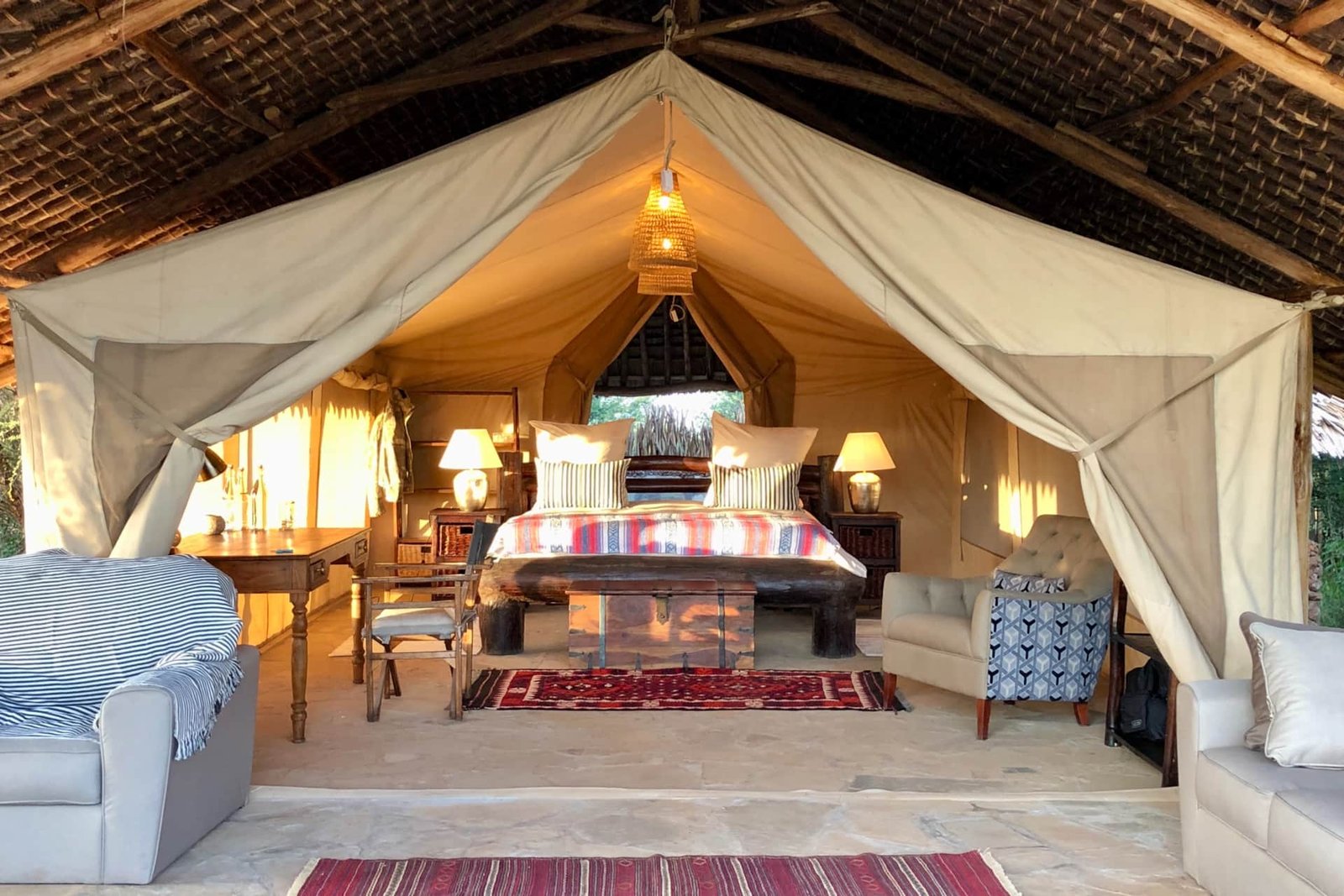 Canvas safari tent interior under thatched roof
