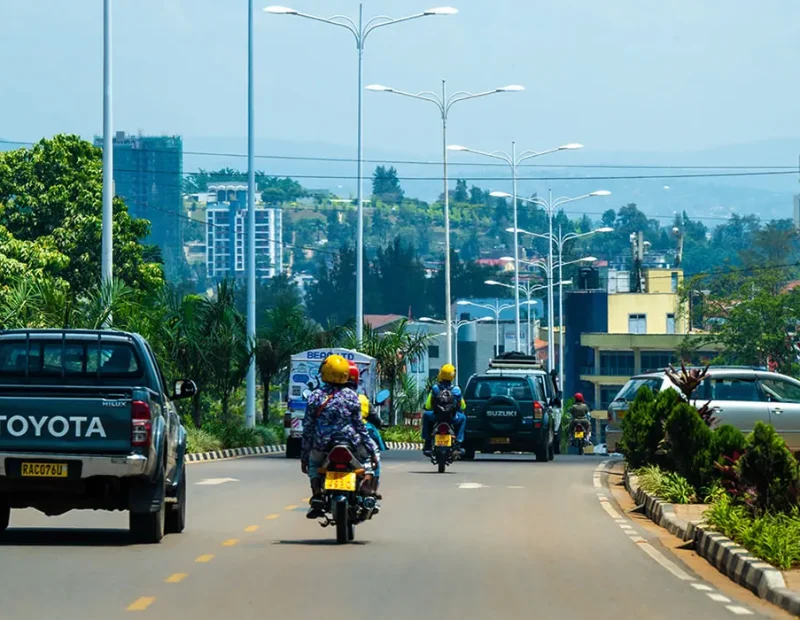 City street with moto taxis and hillside suburbs