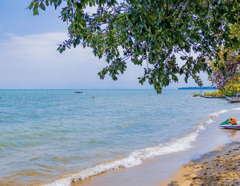 Sandy beach with jet ski under shade tree in Lake Kivu, Rwanda