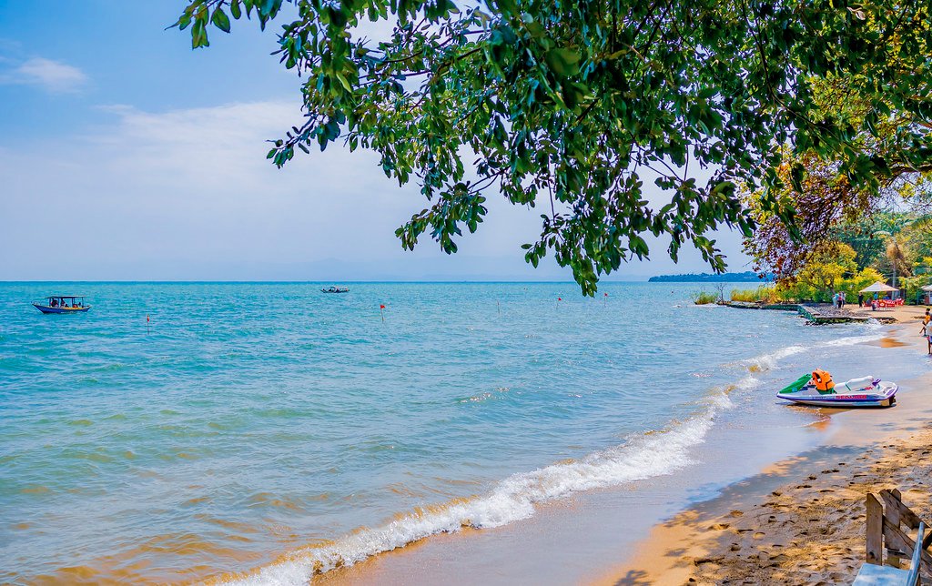 Sandy beach with jet ski under shade tree in Lake Kivu, Rwanda