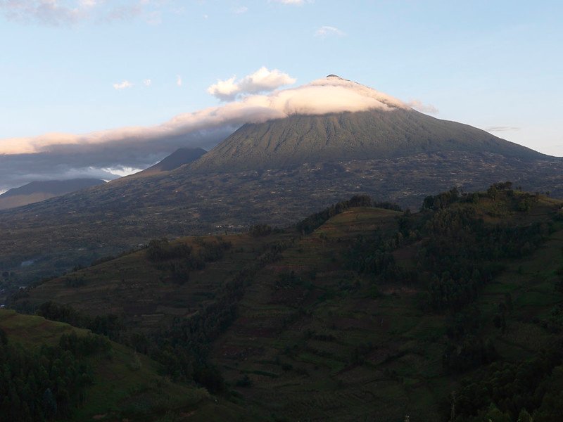 Cone with cloud collar above terraced farmland in Volcanoes, Rwanda