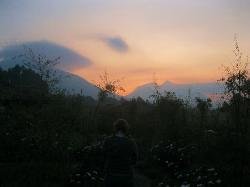 Guest watching sunset from lodge garden in Volcanoes, Rwanda