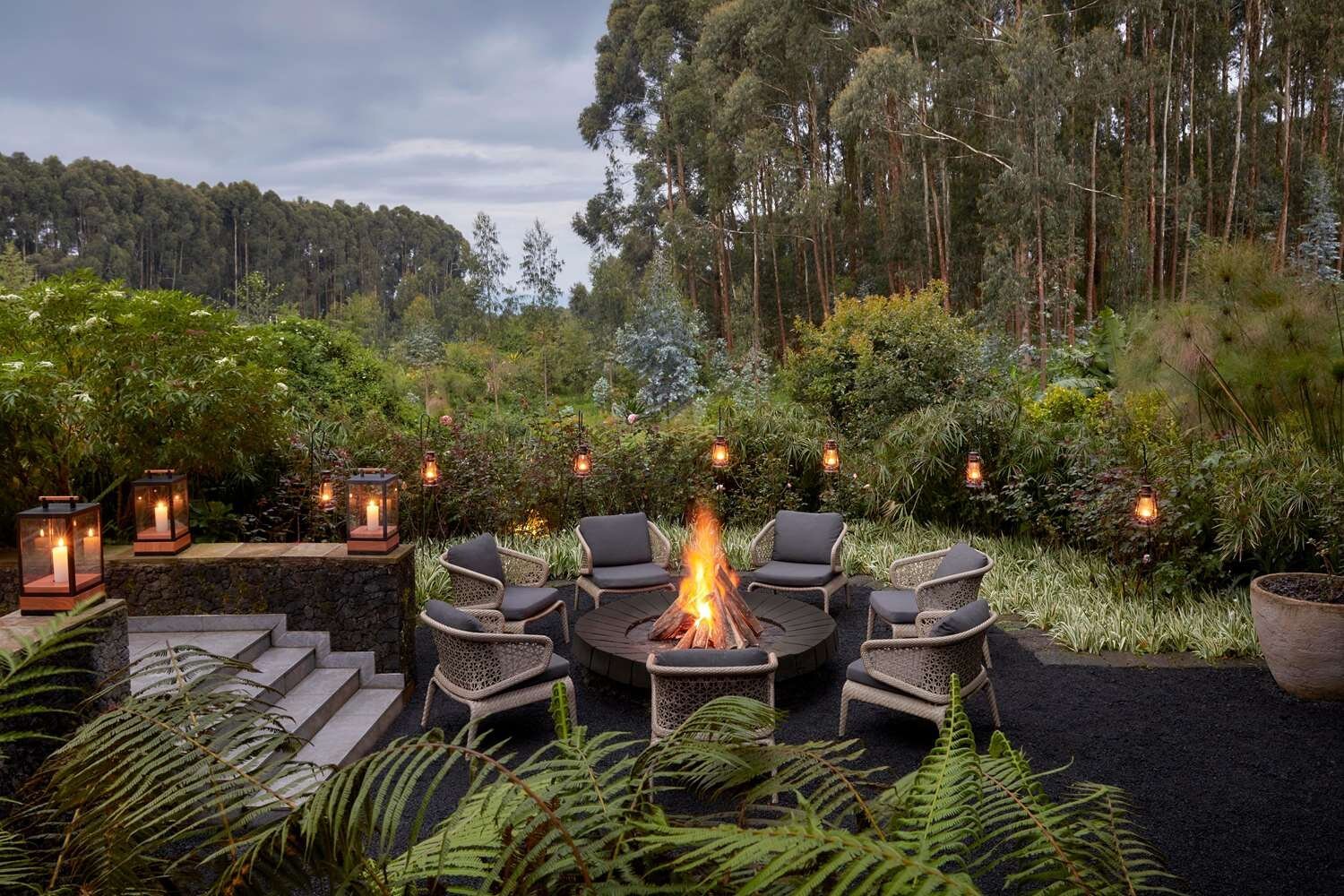 Lodge fire pit lounge with lanterns at dusk in Volcanoes, Rwanda