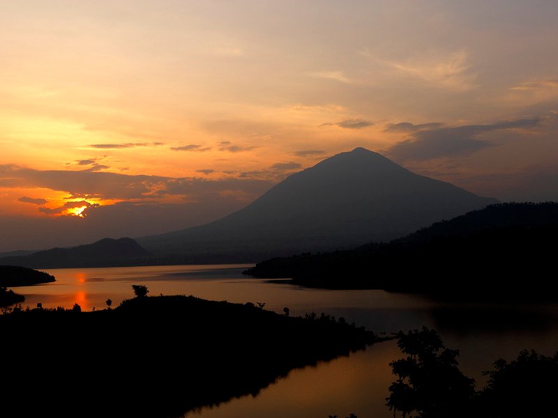 Sunset over lake with volcano silhouette in Volcanoes, Rwanda