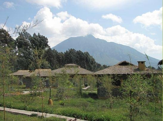 Thatched lodge cottages below volcano in Volcanoes, Rwanda