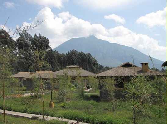 Thatched lodge cottages below volcano in Volcanoes, Rwanda