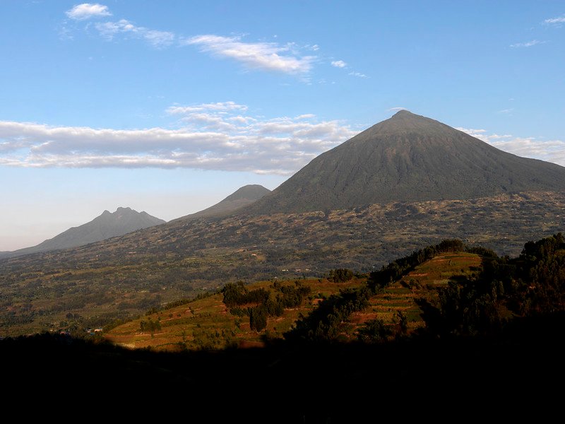Virunga peaks at golden hour over terraced hills in Volcanoes, Rwanda