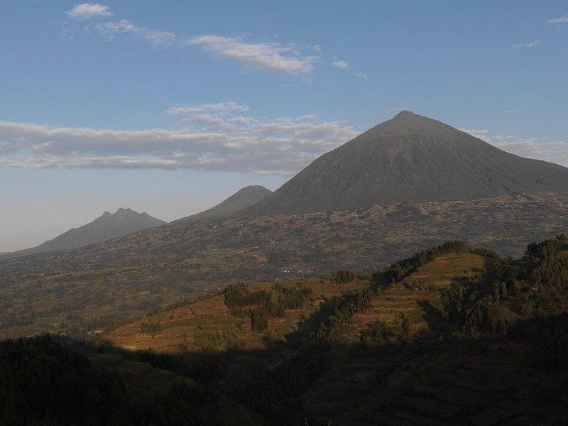 Virunga peaks in blue haze above farm terraces in Volcanoes, Rwanda